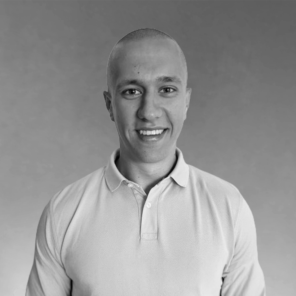 Robert Tiger headshot of smiling bald man in polo shirt against a gray studio background